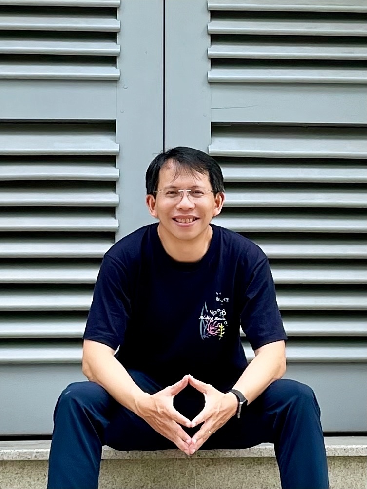 Man wearing a light blue denim shirt pointing right with a smile